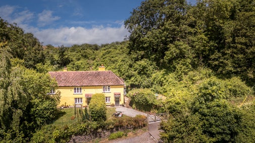 An aerial view of Crockers Cottage, a yellow semi-detached cottage with a red-tiled roof, Devon